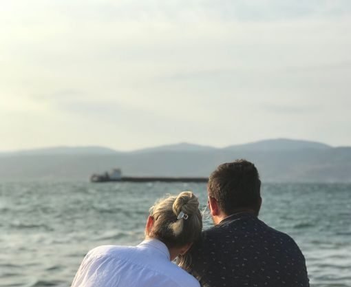 A couple sitting by the sea in İzmir, Türkiye, enjoying a serene vacation moment.
